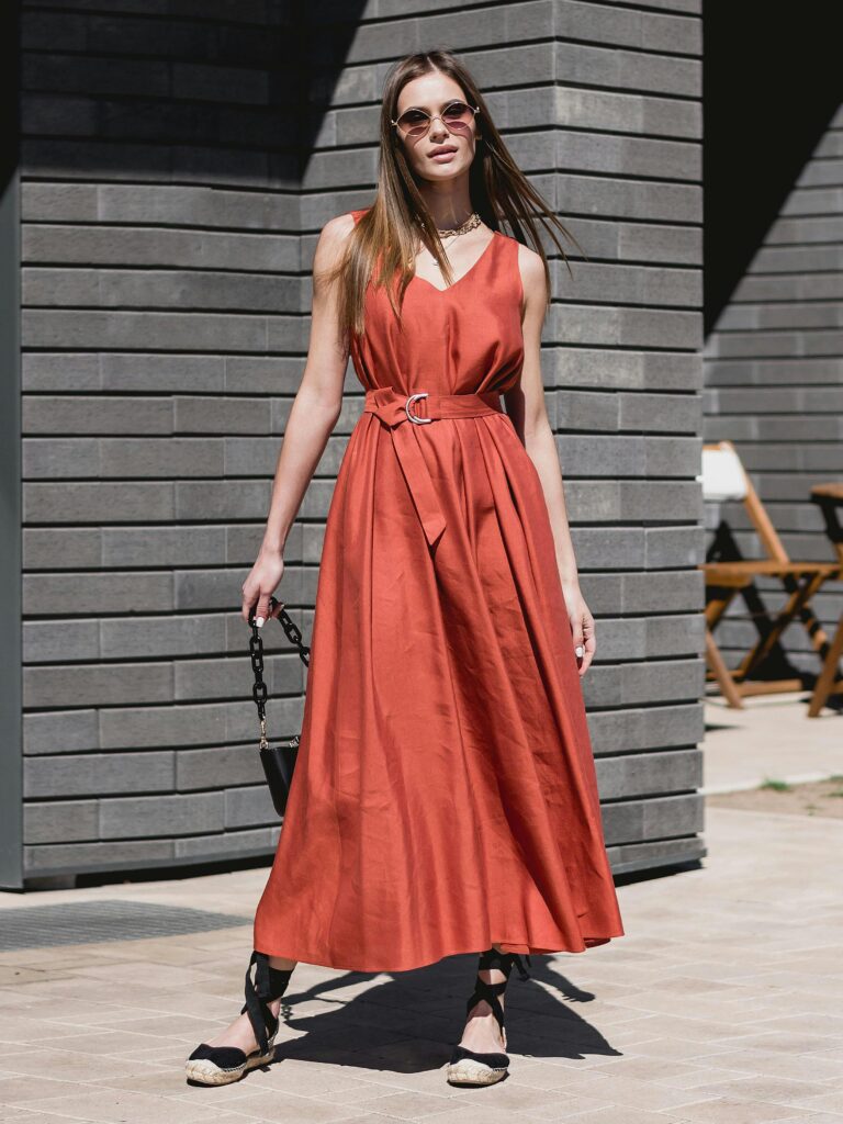 pexels-photo-17048477-17048477 Stylish woman in a red dress with sunglasses posing confidently outdoors.